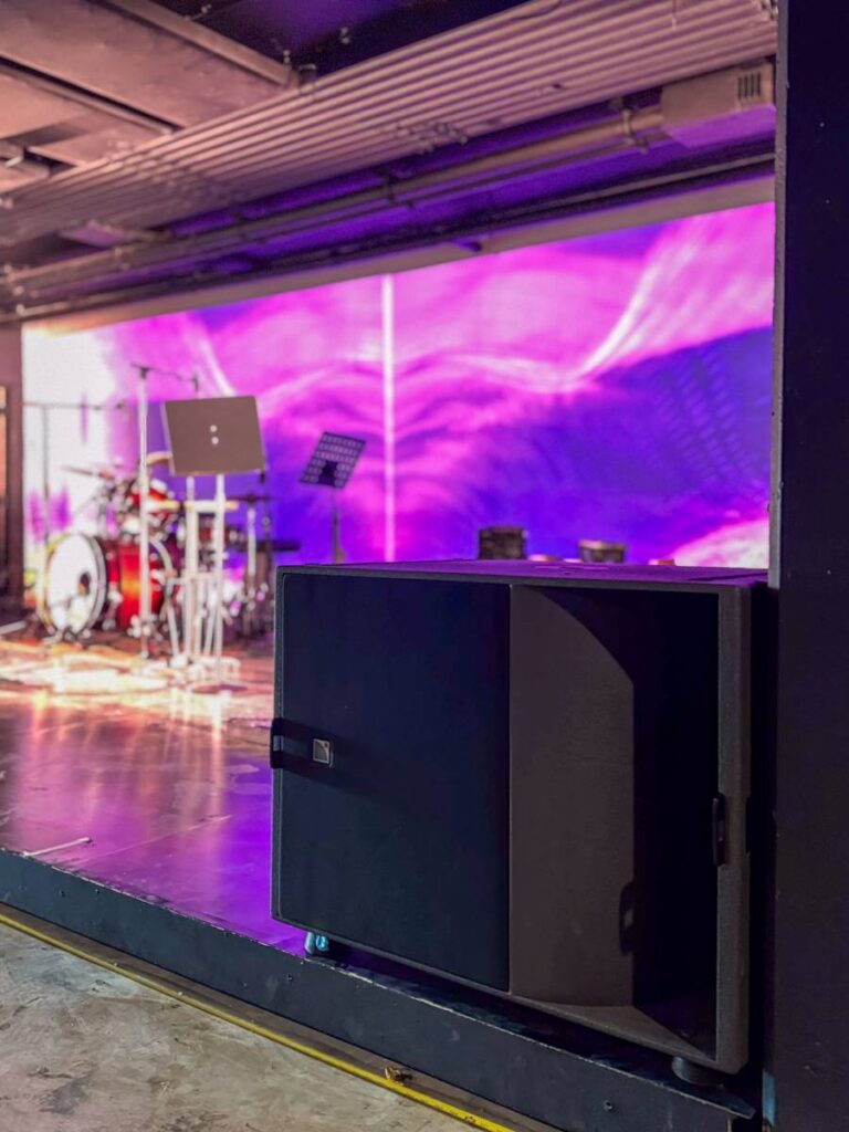 Ground-stacked L-Acoustics KS21 subwoofers provide powerful, consistent low-end coverage specifically tuned for the venue's intimate standing area